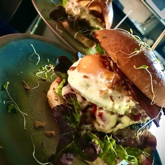 Hamburguesa con huevo frito sobre pan brioche artesanal dorado.