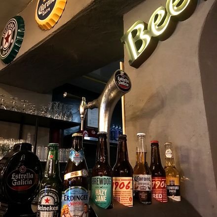Botellas de cerveza y tirador bajo el rótulo luminoso de la barra.