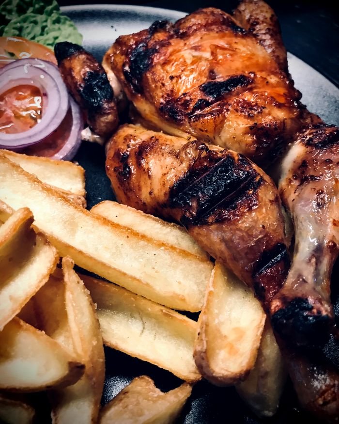 Gallito entero a la parrilla, dorado y marcado, servido con patatas y ensalada.