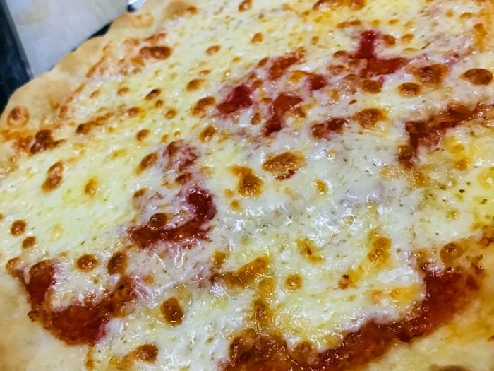 Pinsa romana alargada con tomate, mozzarella y albahaca sobre tabla de madera.
